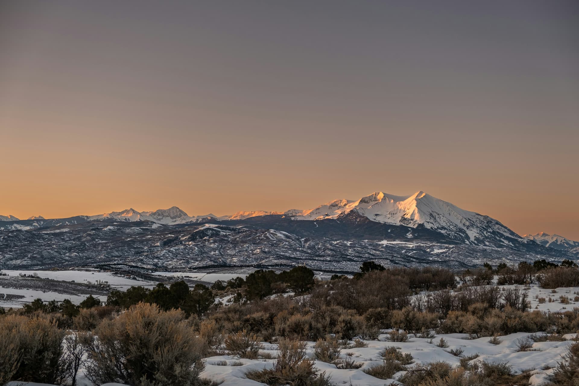 Snow-covered peaks glowing at dusk above the sagebrush near Carbondale