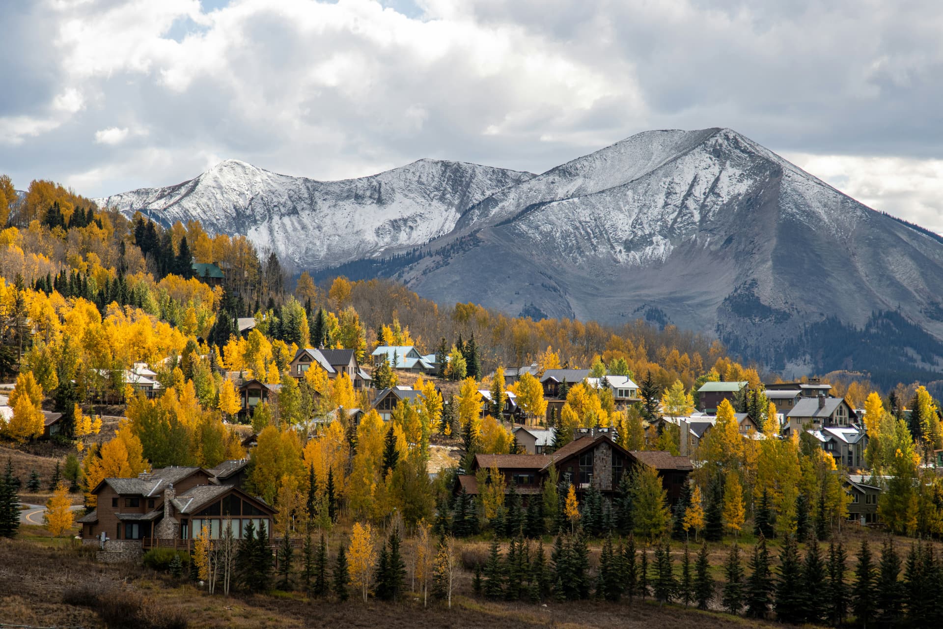 Homes among golden fall aspens beneath snow-dusted peaks in Crested Butte