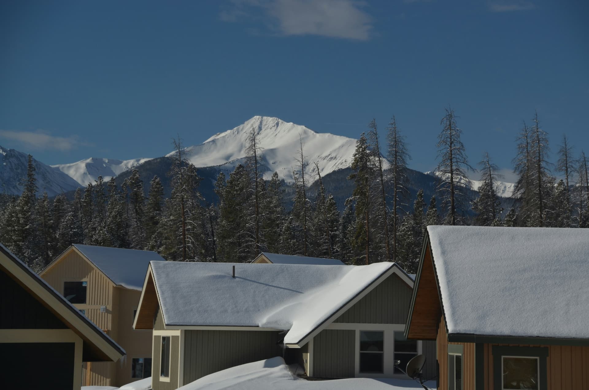Snow-covered rooftops in Winter Park below a snowy peak