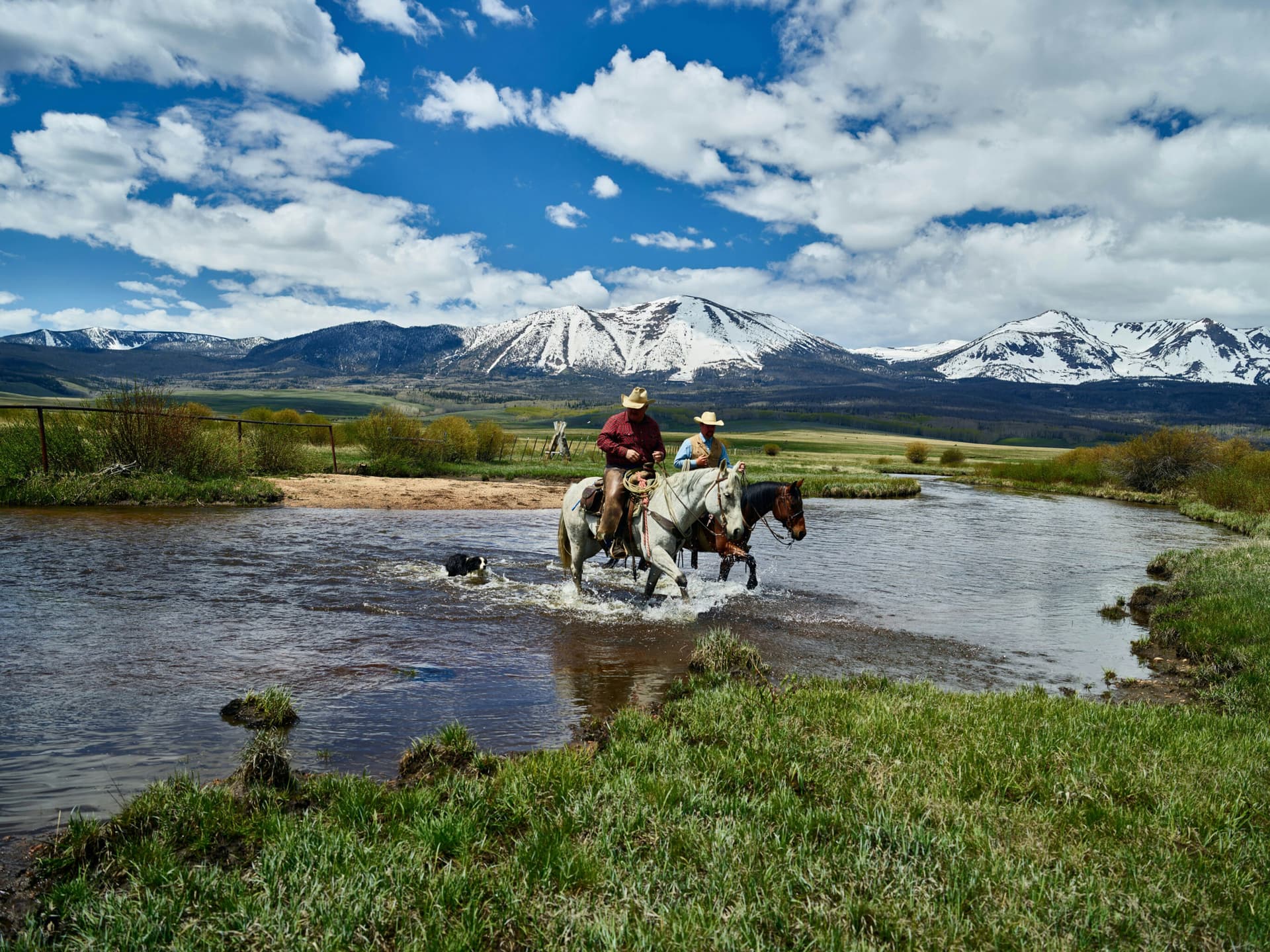 Riders crossing a river on a North Park, Colorado ranch below the snowy Park Range
